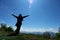 Tourists Woman in a sweater standing on the cliff, with raised hands and looking to sky and mountain