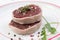 Tournedos: a small round thick cut from a fillet of beef in a white plate background