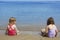 Tow sisters sit on beach bathing suit swimsuit