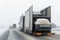 Tow truck car carrier semi trailer on highway carrying batch of new wrapped electric SUVs on motorway road at heavy