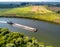 Towboat transports barge with sand along tranquil river