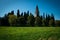 Tower of Basilica di Aquileia in Italy with meadows, trees, cypress and clear blue sky