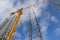 Tower construction crane and reinforcements steel bars against the blue sky. Big yellow construction crane. Close up steel