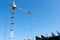 Tower crane on the background of the blue sky in the lower part of the picture part of the building under construction