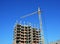 Tower Crane and Building Constructors on Construction Site. Building cranes on construction site with builders. Building high rise