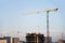 Tower crane constructing a new residential building at a construction site against blue sky