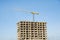 Tower crane constructing a new residential building at a construction site against blue sky. Renovation program