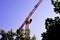 Tower crane construction rotary with an arrow on the background of the sky and trees. Lifting machine spatial movement of goods,
