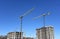 Tower crane lifting a concrete bucket at construction site. Workers during formworks and pouring concrete through a Ñoncrete pump