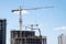 Tower crane lifting a concrete bucket at construction site. Workers during formworks and pouring concrete through a Ñoncrete pump