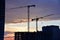 Tower cranes in action at construction site on sunset background. Crane the build the high-rise building