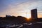 Tower cranes and building silhouette at construction site on sunset background. Heavy mixer concrete truck.