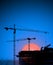 Tower cranes and building silhouette at dawn.