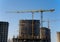 Tower cranes constructing a new residential building at a construction site against blue sky. Renovation program