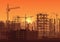 Tower cranes on construction site in sunset. Buildings under construction in sunrise. City skyline silhouette vector