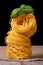 Tower of dry pasta nest closeup with green basil