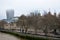 The Tower of London and The City with mist from Tower Bridge. Skyscrapers with fog and Thames River walk with trees and people. Lo