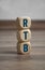 Tower made of cubes and dice with acronym RTB - Real Time Bidding - on wooden background