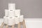 Tower made of white toilet paper rolls against the gray wall in bathroom