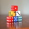 Tower of six colored dice with numbers from 1 to 6 on a wooden