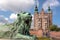 Tower spires over lion bronze sculpture guard at the entrance of Rosenborg Castle, Copenhagen, Denmark