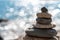 Tower of stones. Balanced pebble pyramid on the beach on a sunny day. Blue sea on the background. Selective focus, bokeh