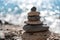 Tower of stones. Balanced pebble pyramid on the beach on a sunny day. Blue sea on the background. Selective focus, bokeh