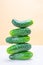 A tower of whole fresh cucumbers on a light neutral background.