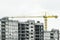 Tower yellow construction crane builds new concrete and cement city building on construction site