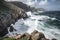 the towering cliffs, surrounded by the azure sea, with waves crashing against the rocks