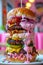 Towering Gourmet Burger with Multiple Patties and Colorful Toppings on a White Plate