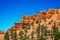 Towering layered rock formations and hoodoos on cliff with dark green pine trees in Red Rock Canyon near Bryce in Utah USA under