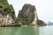 Towering limestone islands over emerald water with growing trees on it that view from cruising tourist boat in summer.