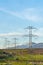 Towering power lines in the valley against snow capped mountain and blue sky