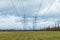 The towers of electric main in the countryside field on the background of blue sky and the forest