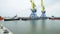 Towing cranes for containers timelapse. Tugboat assisting container vessel to departure after completed loading at the