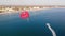 Towing red parachute behind a jetski over the sea along the beach at sunset.