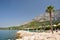 Town Tucepi with sea, palm tree, stones in front and mountain Biokovo in background