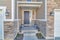 Townhouse front entrance exterior in the middle of a wall with vinyl wood and bricks