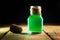 Toxic green drink in magic bottle on black and wooden background. Selective focus