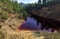 Toxic red lake in abandoned open pit mine in a forest