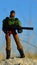 Toy action figure of GI Joe team, named Heavy Duty, standing on coastal rock with minigun