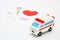 Toy ambulance car and abstract red heart on white background.