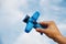 Toy blue plane in a man`s hand on a blue background with clouds sky