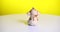 The Toy Brown Monkey Spins On A White Table. Yellow Background. Prores 4k