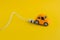 Toy car with charging cable isolated on yellow background , electric car concept and eco-friendly lifestyle