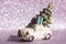 Toy car with Christmas tree on roof on silvered shining background New Year 2022