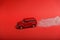 A toy car leaves a glowing trail of confetti on a red background. Valentine`s day. New year`s travel concept