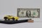 A toy car stands on an electronic scale next to a stand with a banknote, the concept of determining the cost of a car when selling