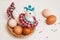 Toy chicken and colored chicken eggs in a wicker brown basket and pastry decorations